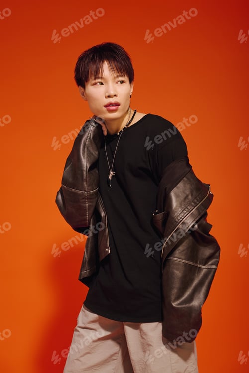 Preview: Stylish young man poses confidently against a vibrant orange background