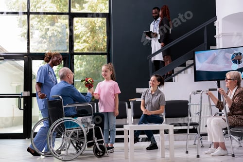 Preview: Granddaughter handing bouquet of flowers to grandfather in wheelchair after finishing medical