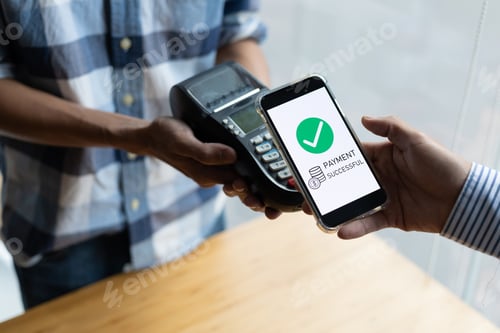 Preview: Close-up of a customer paying for goods with a mobile app on the counter.
