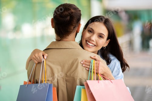 Preview: Cheerful young european lady shopaholic with bags hugging man, enjoy shopping together in mall, back