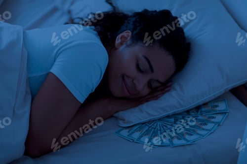 Preview: Smiling Black Woman Sleeping With Dollar Cash Under Pillow In The Night