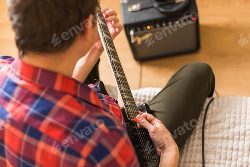 Preview: Young millennial man, guy playing electric guitar. Stay at home, home activity, learning classes