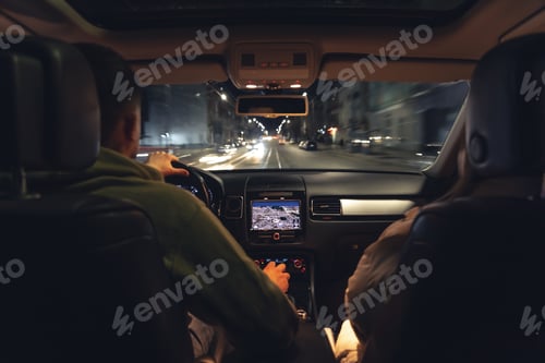 Preview: Man and woman in a car at night, view from the car.