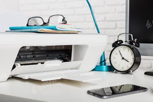 Preview: Printer on desk with glasses, clock, notebook, and smartphone at workspace during daytime