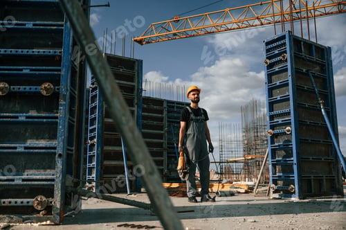 Preview: Standing with grinding machine in hands. Man in uniform is working on the construction site