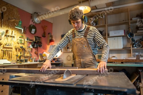 Preview: Carpentry workshop, craftsman master working. Man uses circular woodworking machine.
