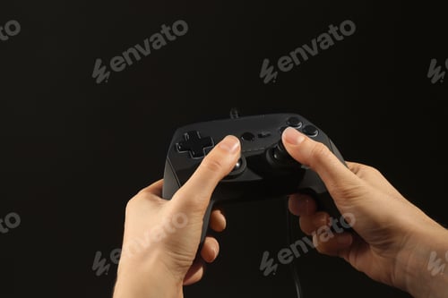 Preview: Woman holding video game controller on black background, closeup