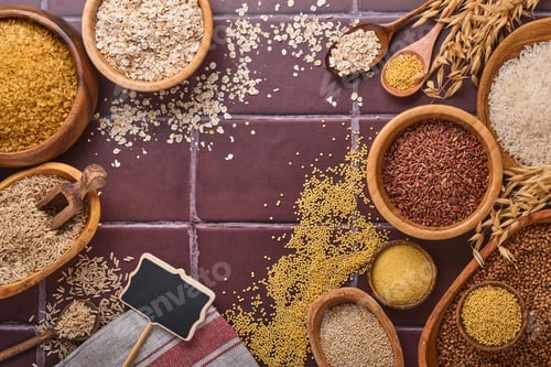 Preview: White, brown and red rice, buckwheat, millet, corn groats, quinoa and bulgur in wooden bowls on a br