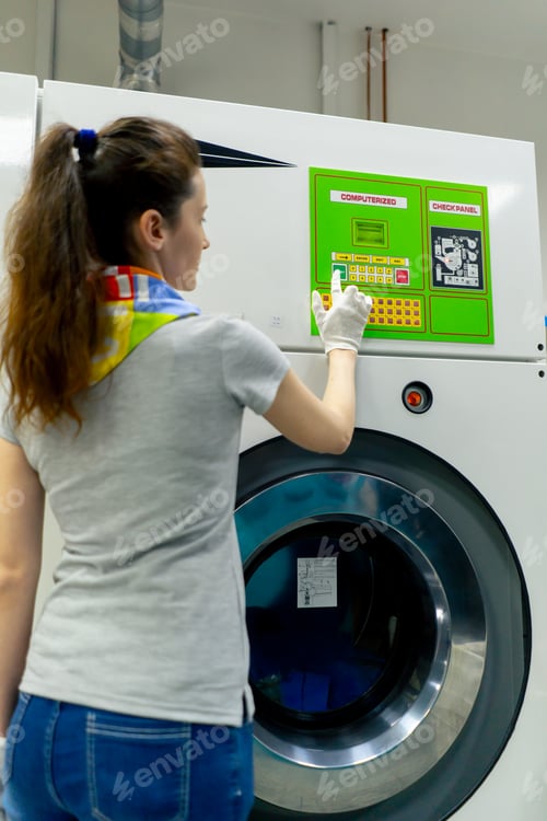 Preview: close up professional dry cleaning young girl presses a button on the green panel of professional