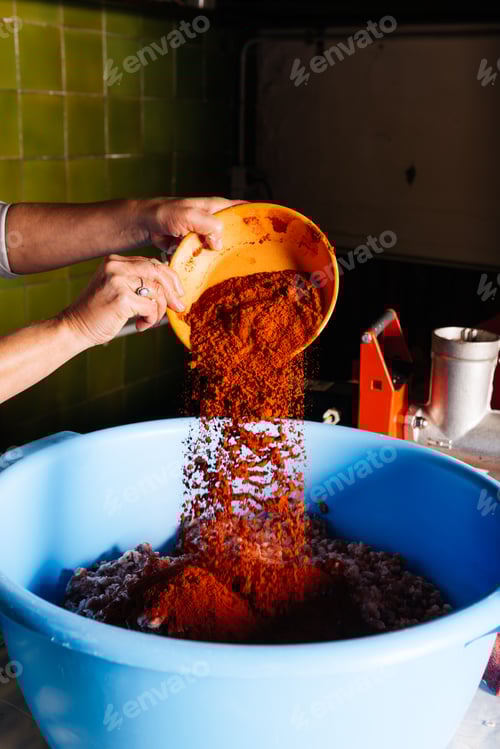 Preview: Crop of woman hands pouring paprika on minced meat in kitchen