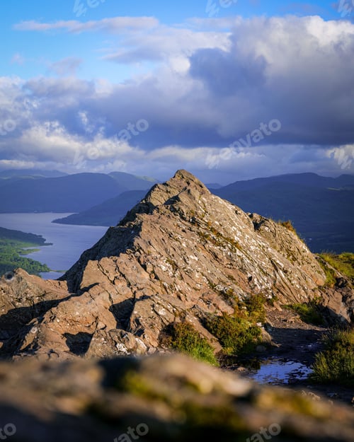 Preview: Rocky peak with lake view and dramatic sky.