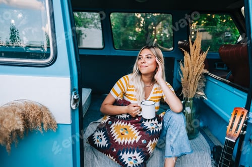 Preview: Woman Relaxing Inside Blue Camper Van with Coffee