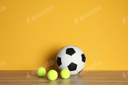 Vista previa: Different sport balls on table against color background. Space for text