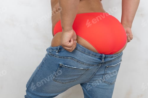 Preview: Cropped rearview of fat obese and overweight female in red lingerie try pull and get dressed in