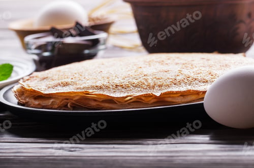 Preview: Stack of French crepes in frying pan on wooden kitchen table
