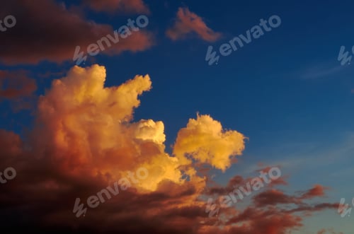 Preview: Fluffy clouds tinted orange by the sunset