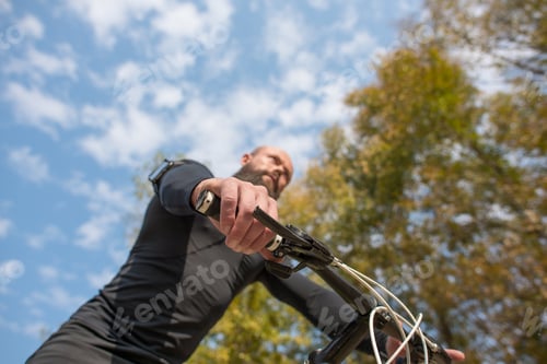 Preview: Bottom view of adult bearded cyclist riding bicycle