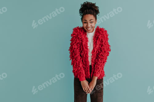 Preview: Shy african american woman in red jacket looking at camera. Front view of smiling black girl with p