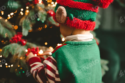 Preview: Little child under Christmas tree. baby boy in Santa Claus hat with gifts under Christmas tree with