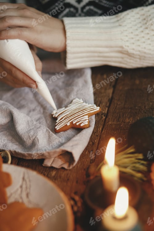 Preview: Hands decorating christmas gingerbread cookie star with frosting on rustic table