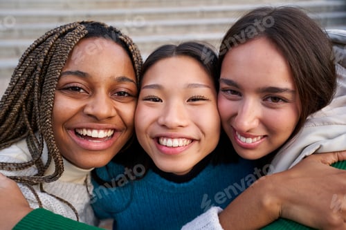 Preview: Cheerful close up portrait of three multiethnic female friends looking at camera with big smiles.