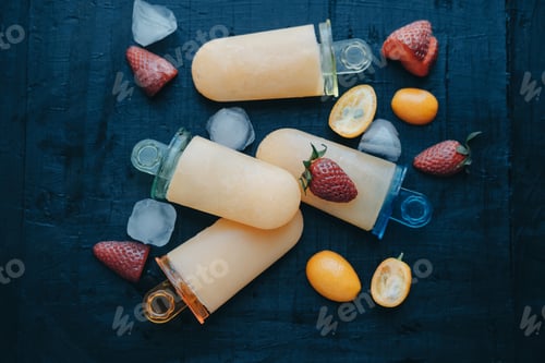 Preview: Homemade fruit ice cream with strawberries and kumquat on a black board.