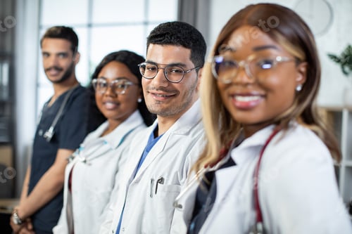 Preview: Close up portrait of happy cheerful multiethnic medical team standing in a row in the hospital