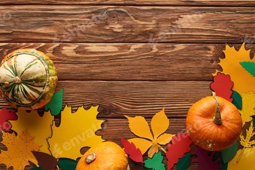 Preview: Top View of Pumpkins on Wooden Surface With Color Paper Leaves