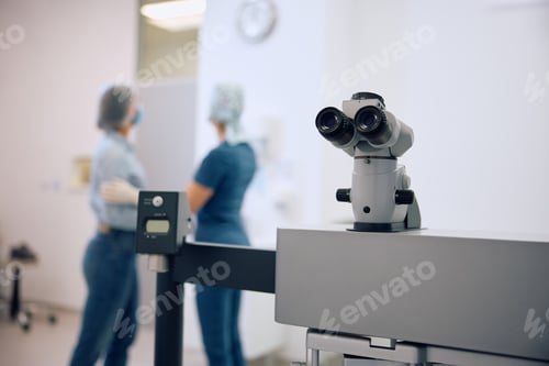 Preview: Close up of ophthalmic microscope with doctor and patient in the background.