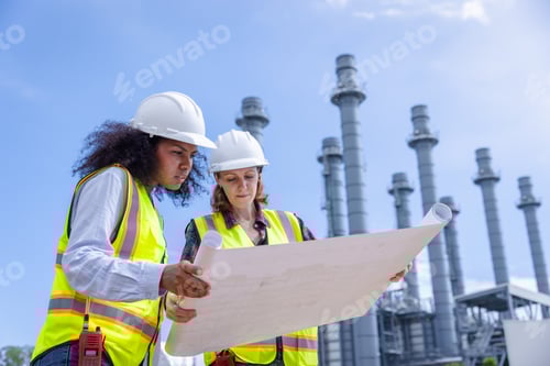 Preview: Female Engineers Reviewing Blueprints at a Power Plant Construction Site in Bright Daylight