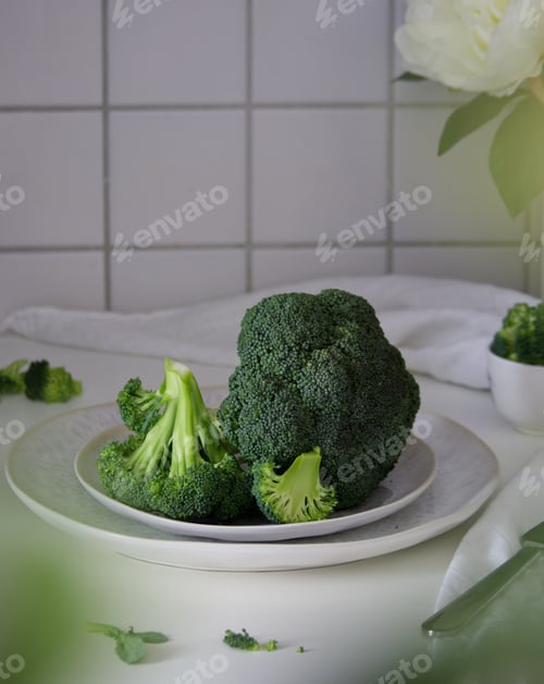 Preview: Green broccoli lies on a white plate on the table close up