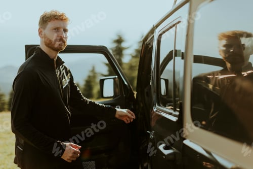 Preview: Young red hair man getting into terrain vehicle on a roadtrip in nature