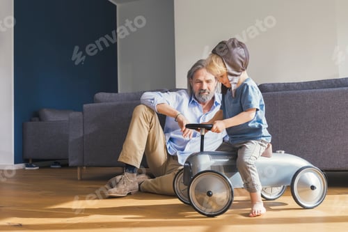 Preview: Grandfather playing with grandson, sitting on toy car