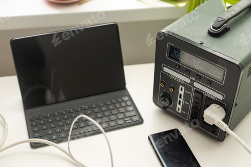 Preview: Portable power station charging gadgets on table in room.