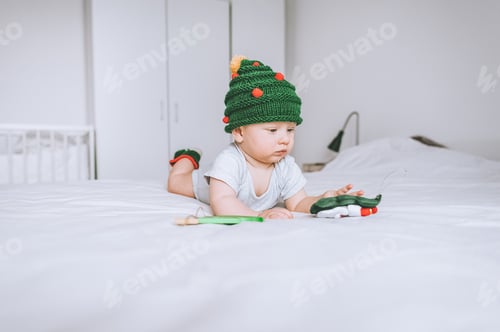 Preview: infant child in adorable christmas tree knitted hat in bed