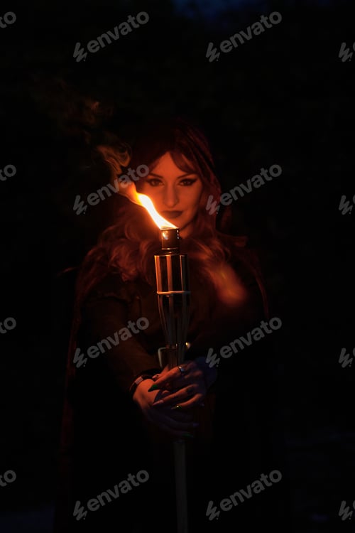 Preview: Woman disguised as a witch holding a flaming torch