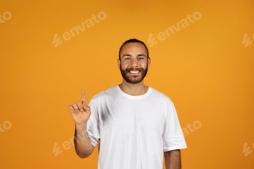 Preview: Cheerful millennial european man in white t-shirt point finger up at copy space, recommends sale