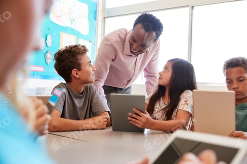 Preview: Teacher among kids with computers in elementary school class