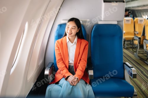 Preview: Attractive Asian female passenger of airplane sitting in comfortable seat while working laptop and