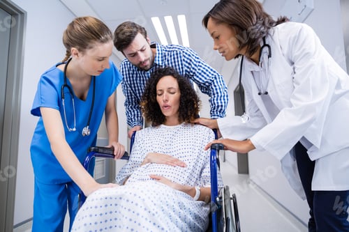 Preview: Doctors and man comforting pregnant woman in corridor