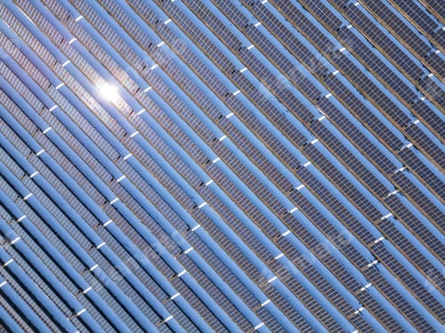 Preview: Aerial view of a large solar farm covered in snow, surrounded by a rural landscape with scattered