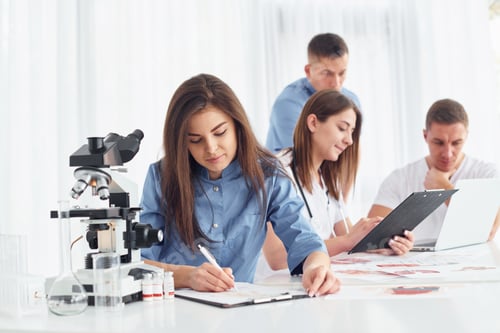 Preview: Woman works with document. Group of young doctors is together in the office