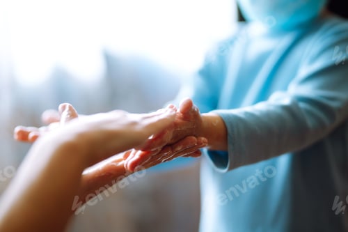 Preview: Mom helps her chaild wash her hands. They are rubbing their hands together creating foam with soap.