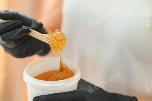 Preview: Portrait of a female caucasian beautician holding a jar of sugar paste for sugaring