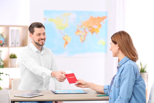 Preview: Male manager giving passport with ticket to client in travel agency