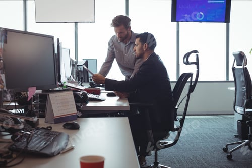 Preview: Male business colleagues discussing over documets at desk