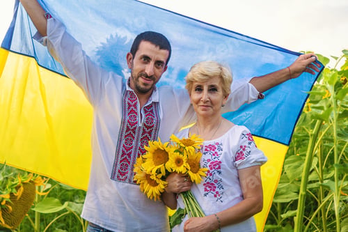 Preview: Mother and son in a sunflower field wearing an embroidered shirt. Selective focus.