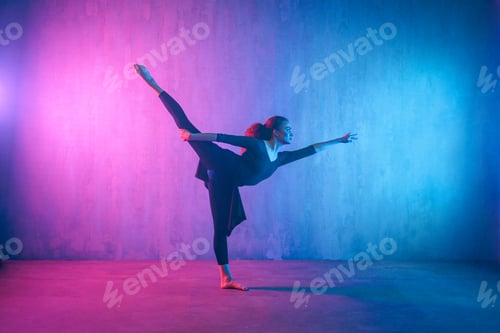 Preview: Modern dance girl dancer dancing in neon light doing gymnastic exercises in studio, copy space.