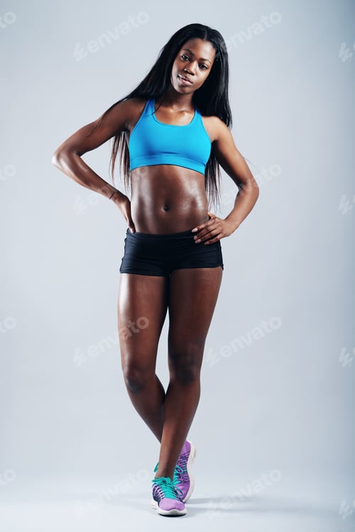 Preview: Showing off her fit figure. A young woman in sportswear posing against gray.