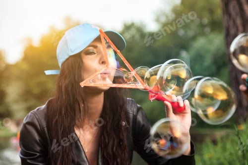 Preview: Mother with son having fun on green lawn with soap bubbles in summer public park, together in sunny